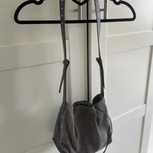 Grå axelremsväska från Zara - Grå axelremsväska i mocka med nitar i remmen säljes🩶 