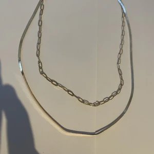 Halsband  - Ett guldhalsband med 2 hängen eller vad man ska säga dem sitter ihop och går ej att ta isär 