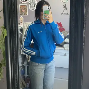 Snyggaste blå adidas zip up me snygg passform. Köpt på myrorna i fint skick.  Storlek XS på mig som är ca 160 och har XS-S i storlek. 