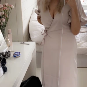 Rosa klänning - Ljusrosa klänning med puffärm och snörning i midjan. Går strax över knäna. Använd 1 gång. 