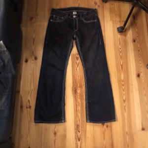 True religion jeans - Midjemått: 47cm Innerbenslängd: 79cm Benöppning: 26cm Få skador längst ner på byxan som syns på bild 2 och vad jag skulle kalla factory disstress på höger  lår Och en stitch som är lite lös tagen också klippt på mitten. De är även färgade svart