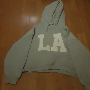 Ljus blå LA hoodie - Har andvänts några gånger fin färg är inte så lång den når typ vid naveln på mig, fråga mig vad som