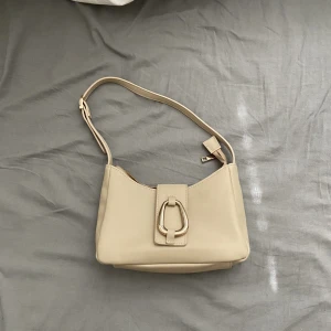 Biege handväska  - Biege handväska med guld detaljer, använd en gång💛