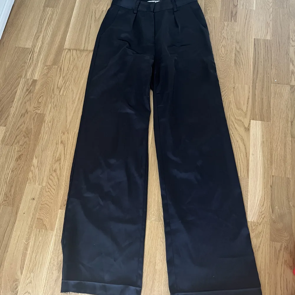 Svarta kostymbyxor i siden från NA-KD, har sprättat upp sömmen längst ner för att de ska bli lite längre, men inga skador för det, annars bra skick. . Jeans & Byxor.
