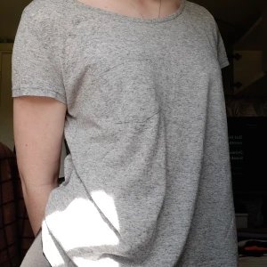 T-shirt - Grå t-shirt med en liten ficka på vänsta bröstet. Ganska tretchig och man kan knyta den den där bak för att få den att sitta lite tightare💗