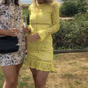 Gul klänning i spets - Klänning i spetsmaterial, öppen rygg med knyte i halsen.