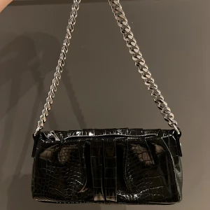 Svart axelväska med kedjeband   - Säljer en svart axelväska med snakeprint som passar till allt 🙌🏼den är rätt så liten men jag har alltid fått plats med allt jag vill i den 