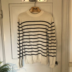 Stickad randig tröja - Crèmevit stickad tröja med mörkblåa ränder. Bra skick utan några defekter. Nypris: 1000 kr. Skriv gärna om du har några frågor!