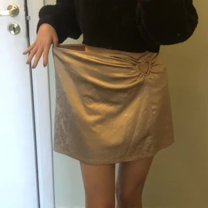 Guldig kjol med hjärta - Storlek s, men stor i midjan! Säljer för den inte passar. Har använts en gång (med säkerhetsnål)! Har ett bedårande hjärt-cutout vid höften <3