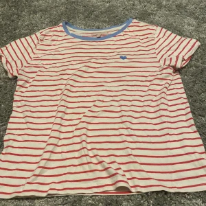 T-shirts  - En super söt och fin t-shirt. Väldigt bra och fint skick. Blå upp till vid halsen. Ett blått hjärta vid höger. Röda smala ränder med tjocka vita ränder. 