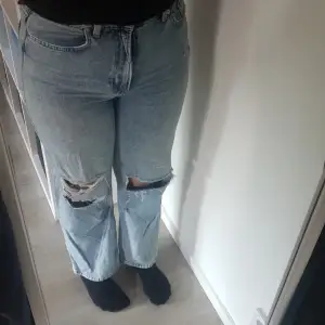 Ett par denim jeans från hm med hål på knäna. 