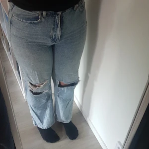 Loose Straight High Waist Jeans - Ett par denim jeans från hm med hål på knäna. 