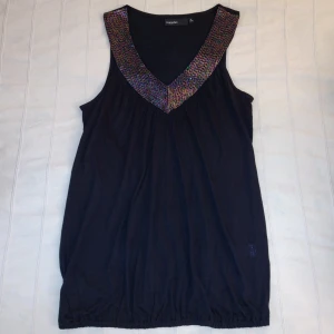 Oanvänd! Mörk v-ringad y2k topp/tunika/linne med "glitter"/pärlor/paljetter - storlek M - Mörk (svart eller någon riktigt mörk plommonfärg eller liknande) v-ringad lite längre topp. Resår i nederkanten. Skitsnygg och oanvänd. Storlek M men passar fler storlekar beroende på hur man vill att den ska sitta. 