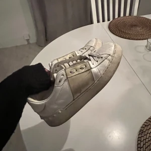 Valentino garavani sneakers - Intressekoll på dessa valentino skor med gulddetaljer i storlek 35,5/36! Slitningar fram coh lite bak på skorna, använda sulor! Kan därav nog gå ner i pris via snabbaffär. Kan möjligtvis fixa sulan och sätta dit en ny! NYPRIS 7000kr