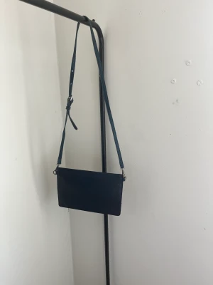 Väska - Säljer denna super fina blåa axelremsväska som är perfekt till alla tillfällen. Väskan är i nyskick och är alldrig använd. Två storlekar av band kommer med i köpet. skriv vid intresse, pris kan diskuteras💕