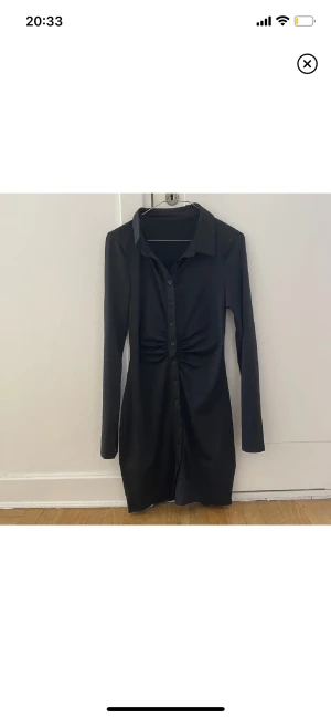 Långärmad svart klänning  - Såå fin och superstrechig och mjuk svart klänning med krage och knappar, samt ruching i midjan som får ens midja att se såå snygg ut. Små slits längst ut i ärmarna för en så snygg look. Endast använd 2 gånger. 