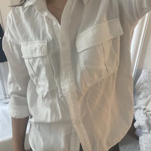 Klassik snygg skjorta - Klassisk vit skjorta. Lös passform med två fickor framtill. Använd ett fåtal gånger. En knapp mitt fram saknas men syns nästan inte när resten av knapparna är knäppta. Går lätt att fixa om man vill! 😊