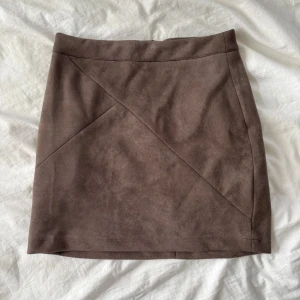 Brun mockakjol från Dennis Maglic - Snygg brun mockakjol från Dennis Maglic i storlek XS. Kjolen har en stilren design med en dragkedja baktill och dekorativa sömmar framtill. 