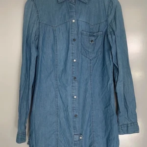 Blå jeansskjorta från TRF Collection Zara Small - Säljer en snygg blå jeansskjorta /skjortklänning från Zara TRF Collection. Skjortan har långa ärmar och knappar framtill samt en bröstficka med knapp. Loose fit