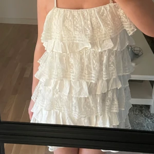 Vit studentklänning med volanger - Säljer en söt vit klänning med flera lager av volanger och spetsdetaljer. Klänningen är  perfekt för sommarens alla tillfällen eller till studenten😊💕
