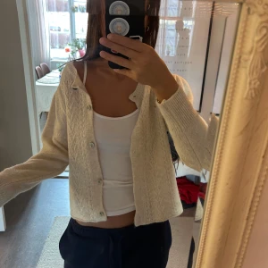 Beige stickad kofta - Säljer en mysig beige stickad kofta med knappar framtill. Perfekt för kyligare dagar och lätt att matcha med olika outfits.