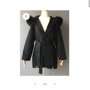 Svart kappa med päls - Elegant svart kappa med pälsdetaljer på axlarna och ett knytbälte i midjan. Köpt förra året för ca 2000kr från FUR Stockholm