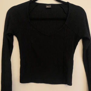 Svart topp gina tricot - Snygg svart ribbad topp med långärmad design och v-ringad hals. Fint skick. Från gina tricot storlek XS. Säljer även den i vit