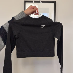 Svart croppad tröja från Gymshark - Svart cropped träningströja från gym shark! Super fin men använder aldrig och därmed säljer jag denna! 💕