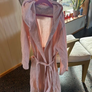 Rosa morgonrock strl 134/146 - Säljer en ljus rosa morgonrock i strl 134-146. Morgonrocken  är 100% bomull. Jag på bilden är 152 cm lång och säljer den pga att den är för liten. Knappast använd och väldigt bra skick.