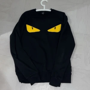Svart tröja med gula ögon från Fendi - Svart och gul Fendi tröja i storlek Large. Köptes för ungefär 6000kr och fick den i present för ungefär 3 år sen och har knappt använt den sedan dess. 