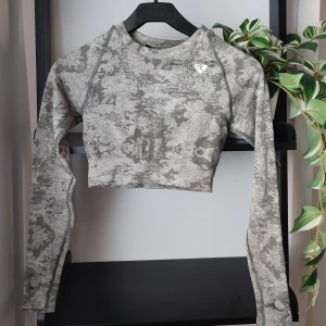 Träningstopp från Womens Best i storlek S - Kamouflage topp i grönt från Women's Best. Storlek S. Otroligt mjukt och stretchigt material. Toppen har tummhål. Jättefin kvalitet, ser ut som ny med alla loggor intakta. Dessvärre har ena armhålan börjat tråda sig lite, dock inget hål vad jag kan se.