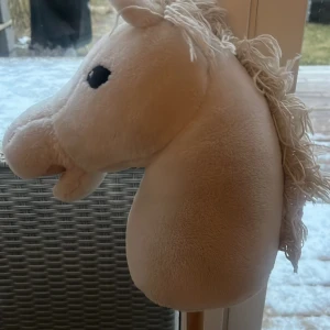 Vit käpphäst - Säljer en söt vit käpphäst med mjuk man och svarta ögon. Perfekt för lek och äventyr inomhus eller utomhus. Hästen har en stadig träpinne som gör den lätt att rida på.