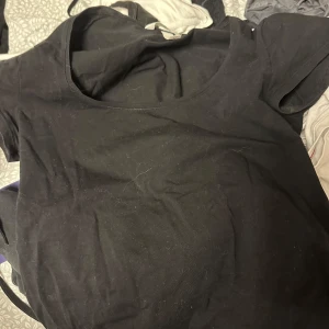 Svart kortärmad topp från H&M - Säljer en enkel och stilren svart kortärmad topp från H&M. Perfekt basplagg för alla tillfällen. Toppen har en rund halsringning och är gjord i ett mjukt material. Sitter som en S🥰