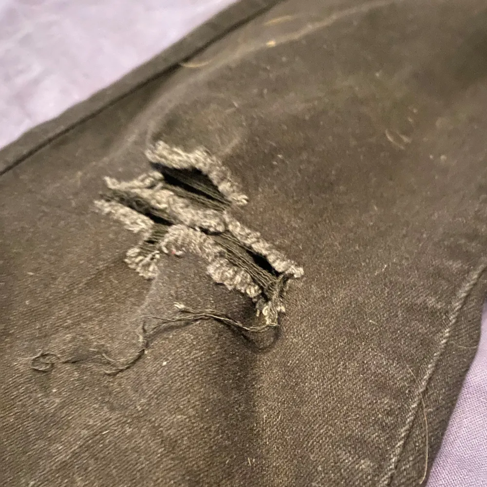 Snygga svarta bootcut jeans med slitna detaljer på låren. De har en hög midja och är perfekta för en trendig look. Jeansen har en klassisk femficksdesign och stängs med knapp och dragkedja.. Farkut & Housut.