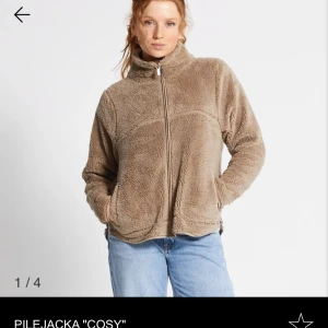 Beige pilejacka 'Cosy' lager 157 - Mysig beige pilejacka med dragkedja och hög krage. Perfekt för kyliga dagar när du vill hålla dig varm och bekväm. Jackan har en avslappnad passform och är tillverkad i mjukt material som känns skönt mot huden.
