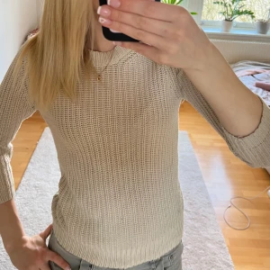 Beige stickad tröja från Zara - Säljer en stilren beige stickad tröja från Zara. Tröjan har trekvartsärmar och en klassisk rund halsringning. Perfekt för en avslappnad och chic look. Passar bra till både jeans och kjol.