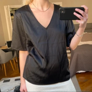 Svart v-ringad blus - Snygg svart blus med v-ringning och korta ärmar. Perfekt för en stilren look.