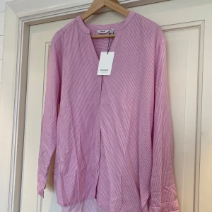 Rosa randig skjorta -  Rosa randig skjorta med långa ärmar och knappar framtill. Aldrig använd med prislappen kvar, nypris 550kr.