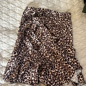 Leopardmönstrad kjol från Chelsea Girls - Snygg leopardmönstrad kjol från Chelsea Girls med volangdetaljer. Perfekt för att ge din outfit en trendig touch. Kjolen har en omlott-design som ger en fin passform.