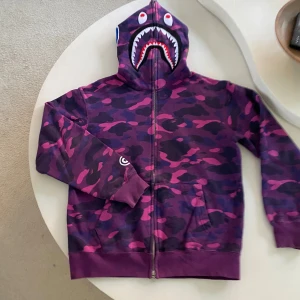 A Bathing Ape (BAPE) Hoodie  - A Bathing Ape (BAPE) Hoodie – Strl M – Knappt använd  Grym hoodie från ikoniska A Bathing Ape (BAPE) – ett måste för alla som gillar streetwear. Klassisk design med hög kvalitet och detaljer som sticker ut. Använd endast ett par gånger, i mycket fint skick. 	•	Storlek: M 	•	Original från BAPE 	•	Knappt använd – som ny 	•	Exklusiv modell, svår att få tag på i butik