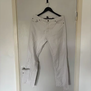 Vita raka byxor i bomull - Snygga vita byxor i 100% bomull med klassisk femficksdesign och raka ben. Byxorna har bälteshällor, metallknapp och dragkedja. Perfekta för en clean och fräsch look året runt.