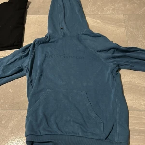 Blå hoodie från Peak Performance M - Säljer en blå hoodie från Peak Performance i storlek M. Tröjan har broderad logga på bröstet, stor känguruficka och huva. Perfekt för chill dagar eller när du vill ha en enkel och snygg look. Mjuk bomullskänsla och klassisk passform.