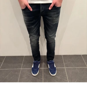 Mörkblå skinny jeans med slitningar - Snygga mörkblå jeans med skinny passform och coola slitningar på knäna. Jeansen har klassisk femficksdesign och är tillverkade i stretchigt denim för en bekväm känsla. Perfekta för dig som gillar en modern och tight stil.