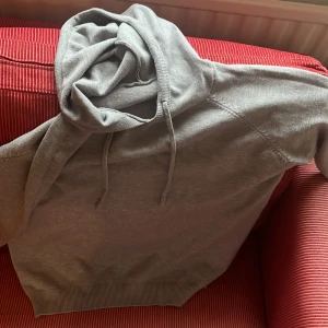Grå hoodie med huva och snörning MERINO TRÖJA  MÖTS GÄRNA I GÖTEBORG ELLER NÄRHETEN  - Enkel och stilren grå hoodie med huva och snörning. Tröjan har ribbade muddar vid ärmslut och nederkant, samt en klassisk passform. Perfekt för chill dagar eller när du vill ha något bekvämt och avslappnat.