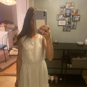 Vit prickig sommarklänning med volang - Superfin vit kortklänning med små prickar och volang nertill. Klänningen är ärmlös och har en lätt, luftig känsla med markerad midja. Perfekt för varma dagar och har ett skirt, romantiskt tyg som ger en söt vibe.