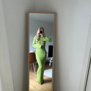 Limegrön ribbad långklänning - Säljer en limegrön, ribbstickad långklänning med lång ärm och öppen rygg. Klänningen har en tight passform och är superstretchig, perfekt för dig som vill sticka ut. Den har en snygg rundad öppning i ryggen som ger en extra cool detalj.