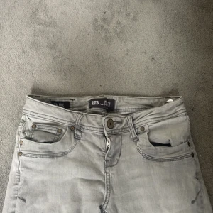 Ljusgrå bootcut jeans från LTB valerie 24/30 - Säljer ett par ljusgrå jeans från LTB med bootcut-snitt. Jeansen har klassiska fem fickor, snygga söm-detaljer på bakfickorna och stängs med dragkedja och knapp. Perfekta för dig som gillar en avslappnad men ändå trendig look. Använd några få gånger 