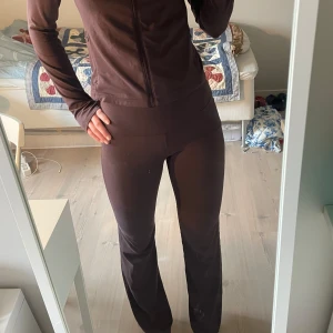 Brunt träningsset  - Mörkbrunt träningsset i stretchigt materia. Tröjan har långa ärmar och en slim passform som sitter snyggt på kroppen. Byxorna är midwaist och bootcut. Perfekt för dig som gillar en sportig och clean stil. 120kr för ett av plaggen och 200kr för båda ☺️