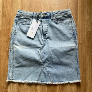 Ljusblå jeanskjol från YAYA - Ljusblå jeanskjol från YAYA med rå kant nertill, klassiska fickor fram och bak samt bälteshällor. Den har en rå kant nertill och snygga sömdetaljer framtill som ger kjolen det där lilla extra. Klassisk femficksmodell med knapp och dragkedja – passar lika bra till vardags som till en utekväll! Aldrig använd, prislappar kvar! Köpt för 799kr. Är i stolek 38 och passar som det. Hör av er vid frågor eller funderingar 💕
