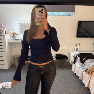 Mörkblå långärmad topp - Säljer en mörkblå långärmad topp med tight passform och djup, fyrkantig ringning. Toppen är croppad och har långa ärmar som sitter snyggt längs armarna. Perfekt att styla med jeans eller kjol för en trendig look.